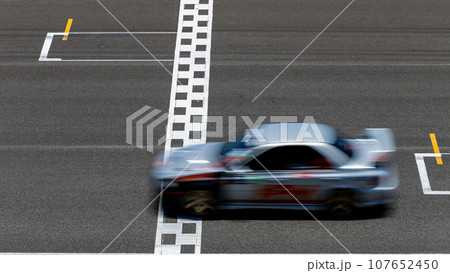 Race car blurred motion crossing the finish line on international circuit speed track, Motion blur Racing car crossing finish line on asphalt race track. Race car blurred motion crossing the finish line on international circuit speed track, Motion blur Racing car crossing finish line on asphalt race track. 107652450