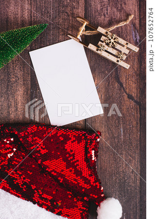 Gift list, christmas tree, sled and santa claus hat on table top and vertical view Gift list, christmas tree, sled and santa claus hat on table top and vertical view 107652764
