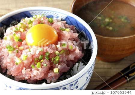 小葱と卵黄が乗っているマグロのたたき丼と熱々のお味噌汁 107653544