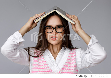 with book on head on grey background 107655590