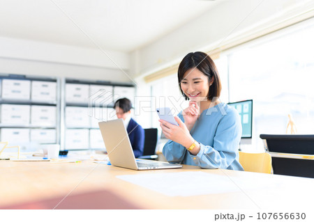 仕事中にスマホを操作する女性 107656630