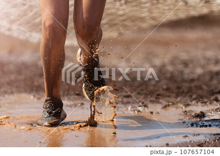 Mud race runners. Crawling, passing under a net obstacle during extreme obstacle race 107657104