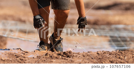 Mud race runners. Crawling, passing under a net obstacle during extreme obstacle race 107657106