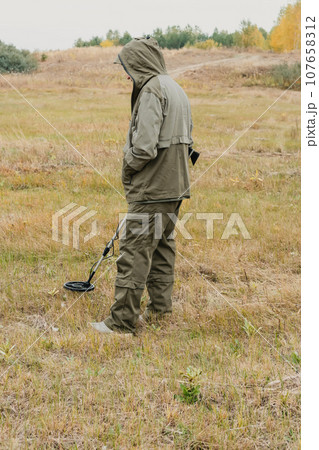 Man with electronic metal detector device working on outdoors. 107658312