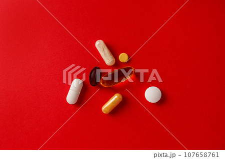 Pharmaceutical medicine pills, tablets and capsules on red background Pharmaceutical medicine pills, tablets and capsules on red background 107658761