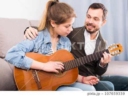 Guitar tutor helping client learn instrument 107659339