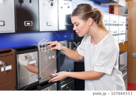 Young female choosing reliable mailbox in specialty shop Young female choosing reliable mailbox in specialty shop 107660551
