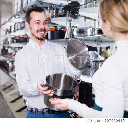 Male seller demonstrating saucepans Male seller demonstrating saucepans 107660915