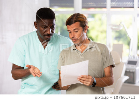 African American doctor consulting patient filling medical form before consultation 107661713