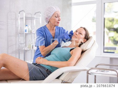 Woman getting procedure of injection contouring and for facial correction in clinic Woman getting procedure of injection contouring and for facial correction in clinic 107661874