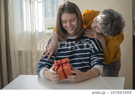 Grandmother make a gift to her grand daughter. Grandmother make a gift to her grand daughter. 107663809