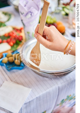 Master class and cheese tasting. Women make cheese. The enzyme and starter culture are added to the milk in a metal container. Milk folding process, home production, business, entrepreneur. 107664769