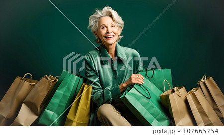 Happy elegant older woman holding green shopping bags. Concept of shopping, sales season, Green Monday, Black Friday Happy elegant older woman holding green shopping bags. Concept of shopping, sales season, Green Monday, Black Friday 107665754