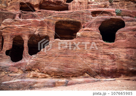 View of the Temples and caves carved into the sandstone rock in the gorge. Petra, Jordan 107665985
