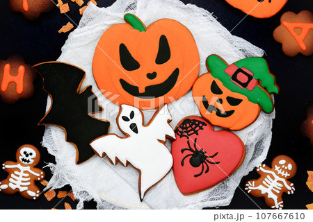 The hand-made eatable gingerbread Halloween pumpkin, ghosts, bat and sceletons on black background 107667610