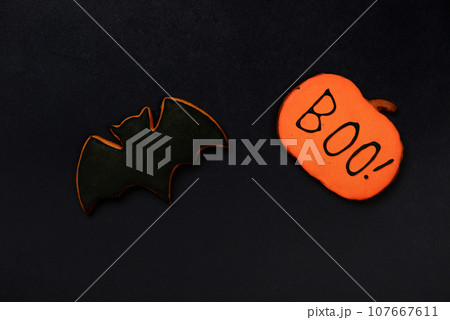 The hand-made eatable gingerbread Halloween  bat and pumpkin with boo inscription on black background 107667611