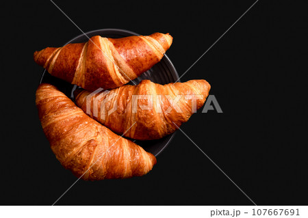Croissants on a black background with copy space. French cuisine concept. Top view Croissants on a black background with copy space. French cuisine concept. Top view 107667691