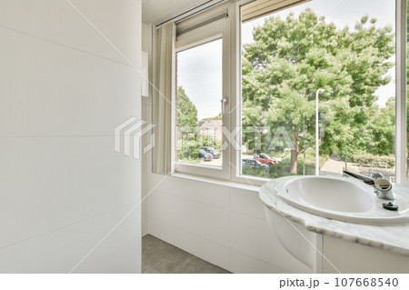 a bathroom with a sink and large window looking out at the trees outside in the photo is taken from inside 107668540