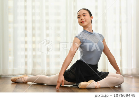 Dedicated Young ballerina in pointe shoes doing stretching exercise on the floor. Classical dance, choreography and art concept Dedicated Young ballerina in pointe shoes doing stretching exercise on the floor. Classical dance, choreography and art concept 107669449