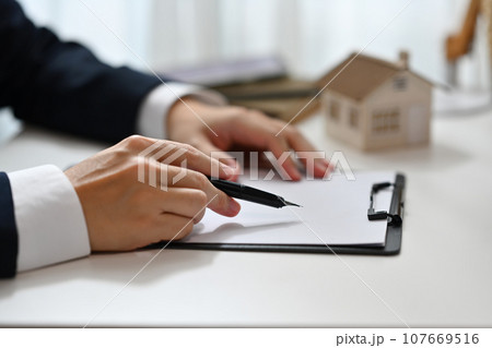 Real estate agent hand holding pen pointing at contract document. Real estate, mortgage, loan and insurance 107669516