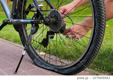 A bicycle with a flat rear wheel parked on a city road A bicycle with a flat rear wheel parked on a city road 107669982