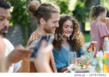 Portrait of couple sitting at the table with family and friends at the family garden party. Portrait of couple sitting at the table with family and friends at the family garden party. 107670682