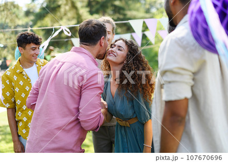 Friends reunite after a long time apart. Men and women embracing, happy to meet at garden party. Friends reunite after a long time apart. Men and women embracing, happy to meet at garden party. 107670696