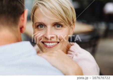 Portrait of beautiful couple in restaurant, on romantic date. Wife and husband touching foreheads, having romantic moment at restaurant patio. 107670722