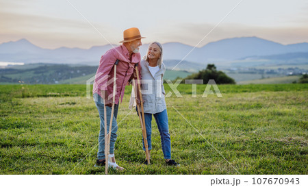 Senior man with broken leg and crutches. Recovery, rehabilitation after injury or surgery in the nature. Wife helping husband with walking during easy walk on their vacation. Senior man with broken leg and crutches. Recovery, rehabilitation after injury or surgery in the nature. Wife helping husband with walking during easy walk on their vacation. 107670943