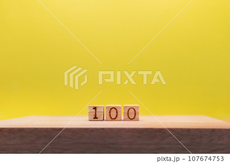 すき間をあけた100の数字のウッドキューブが奥にある黄色い背景 すき間をあけた100の数字のウッドキューブが奥にある黄色い背景 107674753
