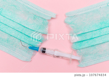 Broken Medical Syringe and Torn Medical Face Mask on the Pink Background 107674834