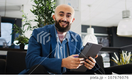 Startup worker using tablet in office, making presentation for executive board briefing meeting. Middle eastern entrepreneur checking data and monthly report, AI developer tasks. 107676076