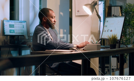 Registrar focused on checking online company documents for mismatching values during nightshift. Employee in office paying attention to paperwork figures, verifying accuracy Registrar focused on checking online company documents for mismatching values during nightshift. Employee in office paying attention to paperwork figures, verifying accuracy 107676127