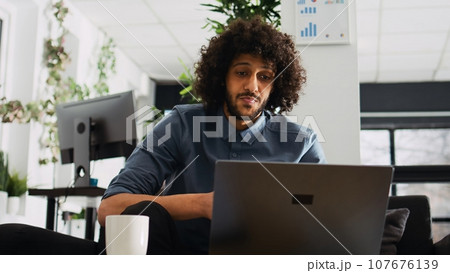 Employee on briefing meeting videocall discussing with manager about new business solutions to increase company profit, videoconference. Young adult on telework call, startup agency. Tripod shot. 107676139