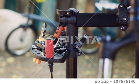 Detailed shot captures assortment of specialized equipment meticulously organized on repair-stand prepared for bike maintenance tasks. View of wrench screwdriver and other tools for bicycle repair. 107676140