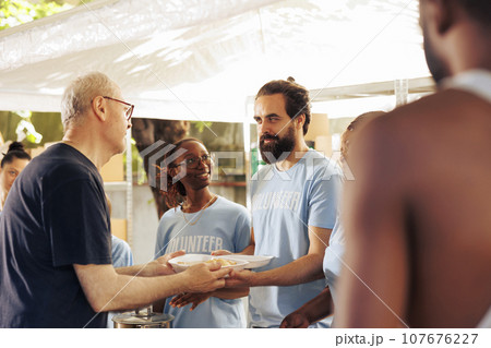 Members of a multicultural community come together, volunteering at non-profit center to donate food and essentials to the homeless and underprivileged. Young volunteers helping the poor and needy. 107676227