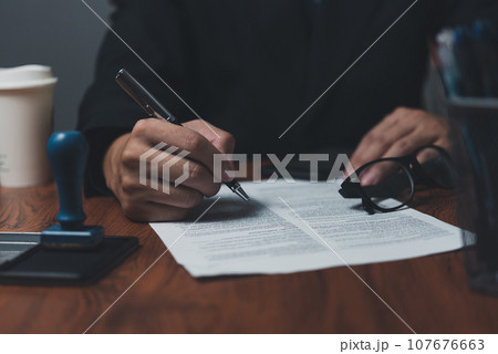 Businessman holding a pen signing a document, law ,job search, write a personal contract on desk. Businessman holding a pen signing a document, law ,job search, write a personal contract on desk. 107676663