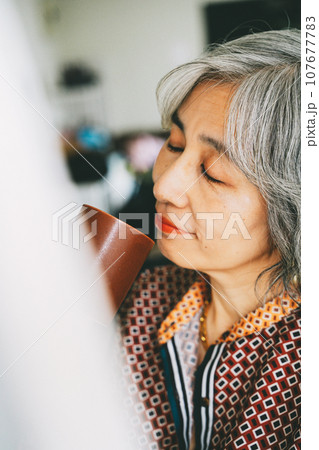 窓辺でドリンクを手にする女性 107677783