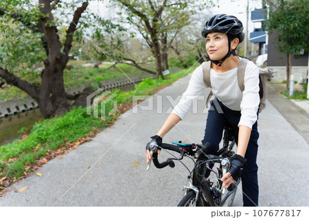 ビジネスカジュアル姿でロードバイクを乗りこなす若い女性 107677817