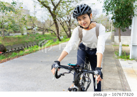 ビジネスカジュアル姿でロードバイクを乗りこなす若い女性 ビジネスカジュアル姿でロードバイクを乗りこなす若い女性 107677820