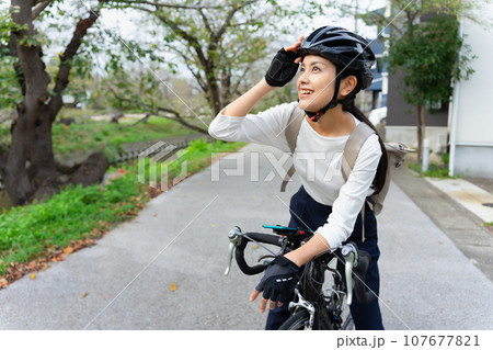 ビジネスカジュアル姿でロードバイクを乗りこなす若い女性 107677821