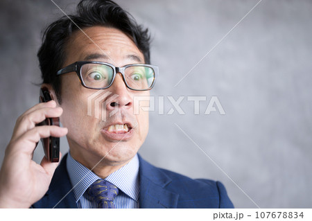 スマホで通話する男性　内容を聞いてびっくりする驚愕の表情のアップ 107678834