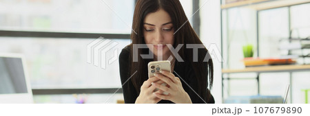 Satisfied woman sends messages to boyfriend from office Satisfied woman sends messages to boyfriend from office 107679890