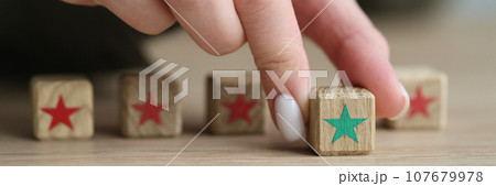 Hand of woman moving kids wooden cube with green star Hand of woman moving kids wooden cube with green star 107679978