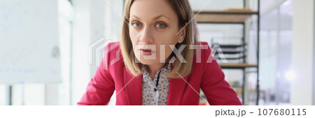Suspicious blonde woman types on keyboard looking in camera 107680115