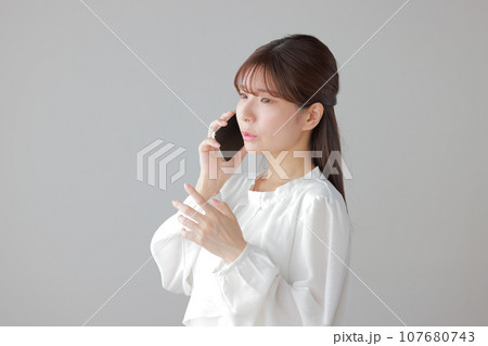 困った表情で電話する若い女性1 107680743