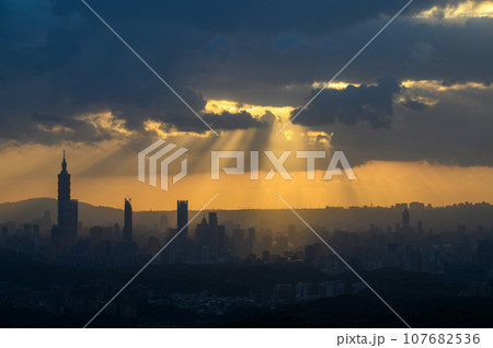 At dusk, the sun breaks through the clouds and shines on Taipei City. 107682536