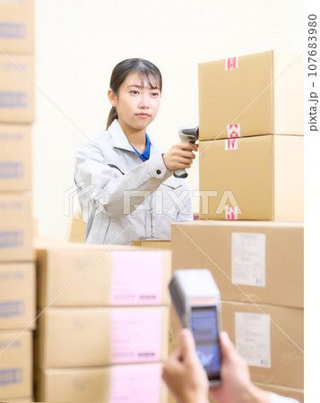 倉庫にてバーコードをスキャンする作業服の女性 107683980