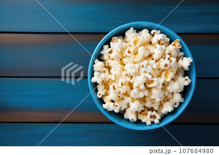 Popcorn in a bowl on a blue wooden background 107684980