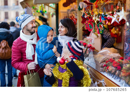 Parents with kids choosing X-mas decorations in market Parents with kids choosing X-mas decorations in market 107685265